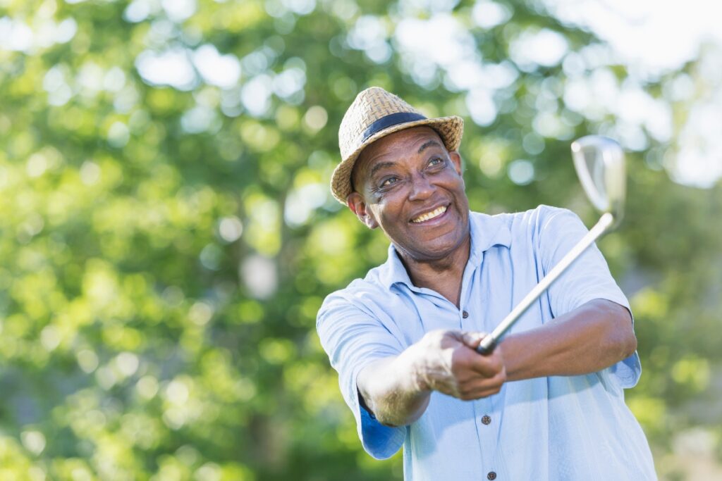 A man sporting arm swinging a golf club in a park.