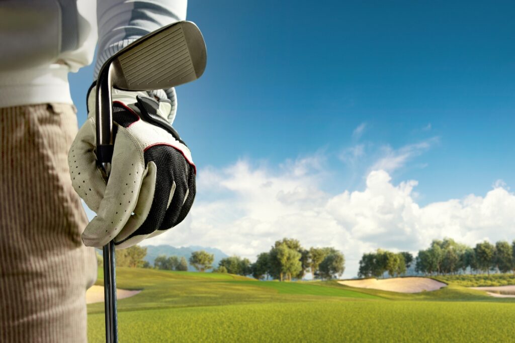 A golfer wearing arm sleeves poses with a golf club on the course.