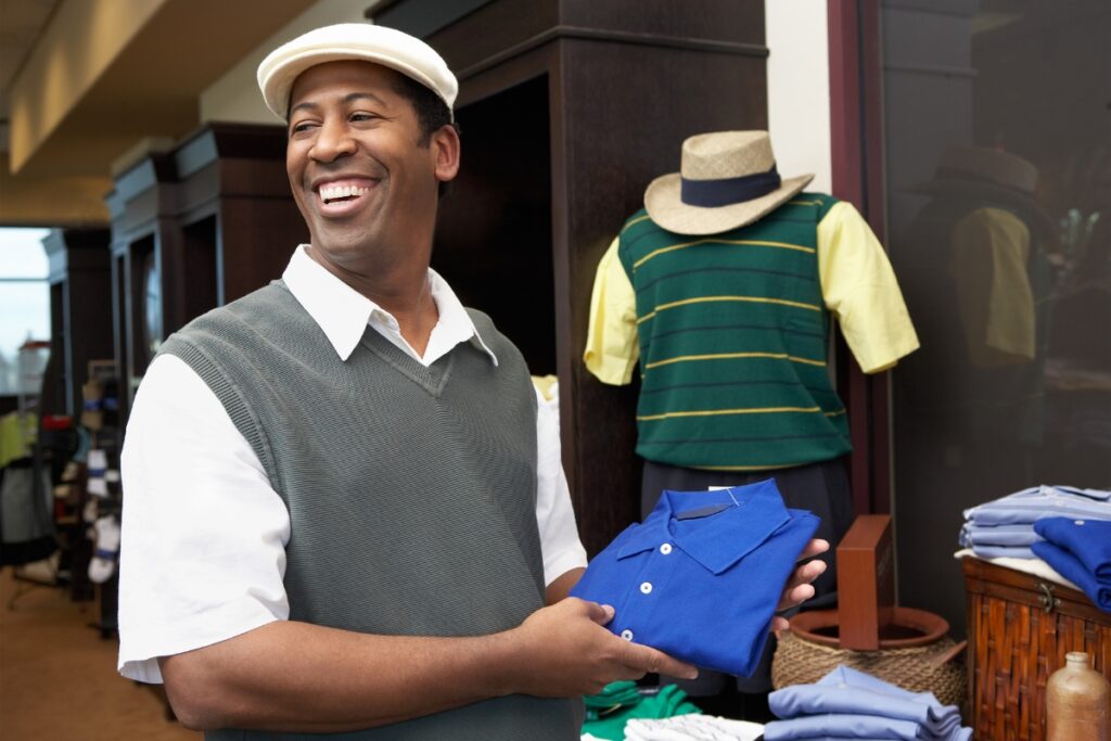 A man smiling in front of a display of golf vests.