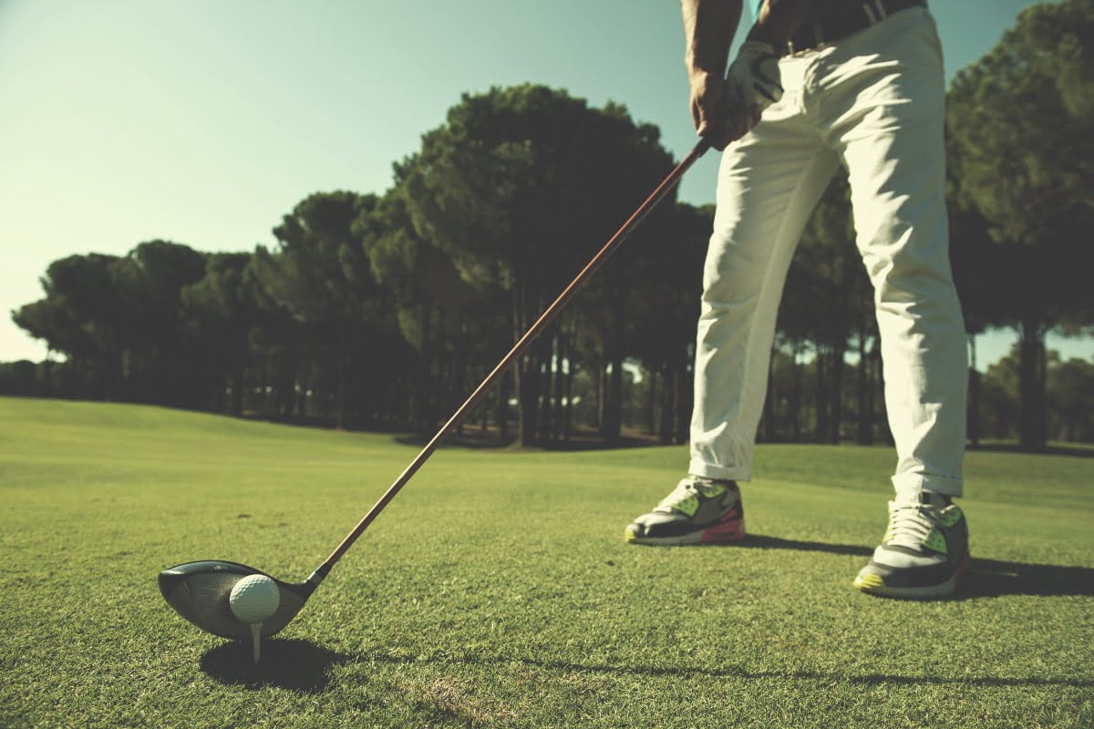 A man is standing on a golf course, braving the winter weather with a golf club in his hand.