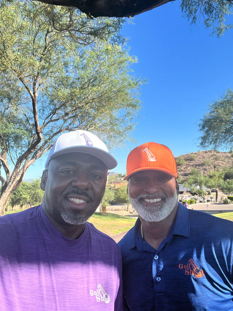 Two men posing for a photo in a park.