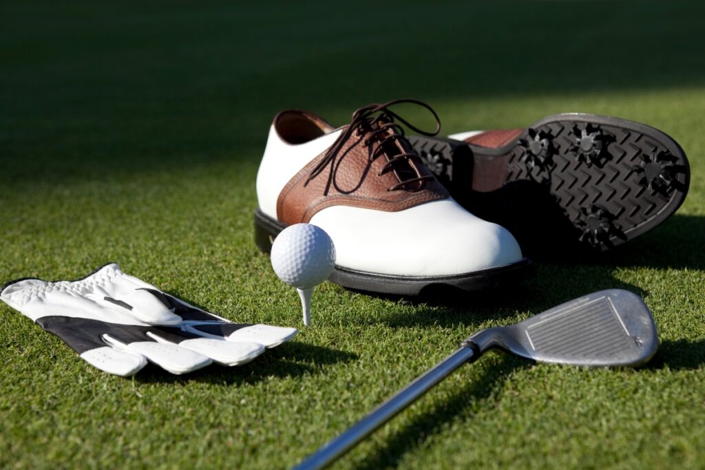 A pair of golf shoes and a golf ball on the grass, emphasizing the perfect combination of golf lifestyle apparel.