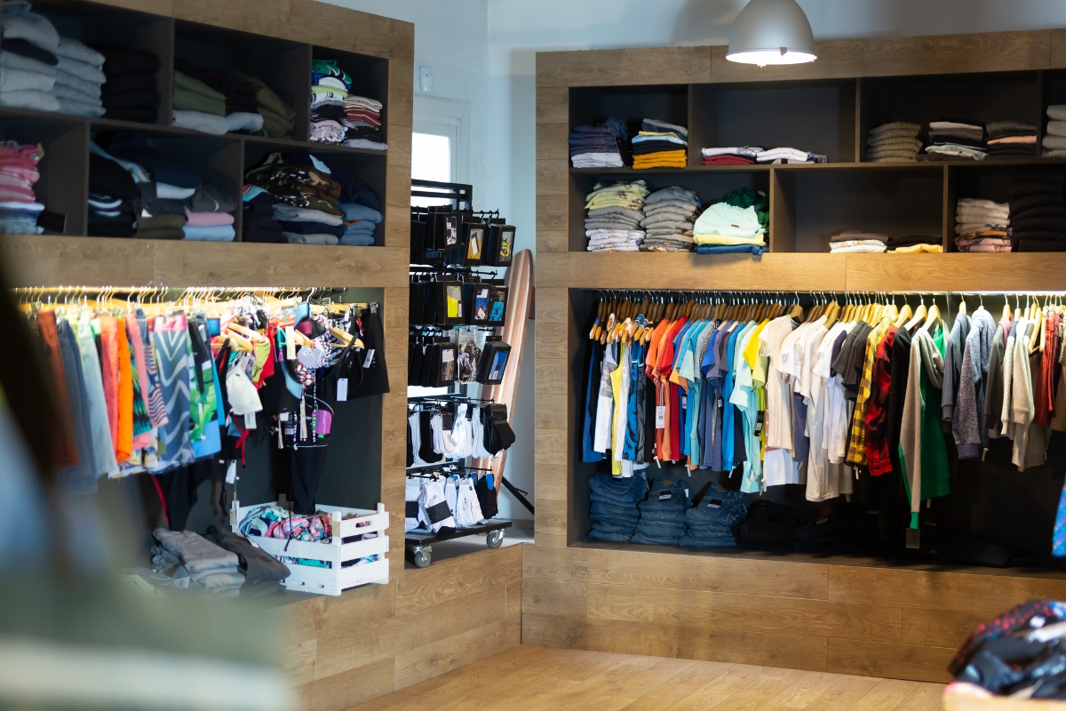 Interior of a clothing store displaying assorted top golf apparel brands neatly arranged on shelves and hanging racks under soft lighting.
